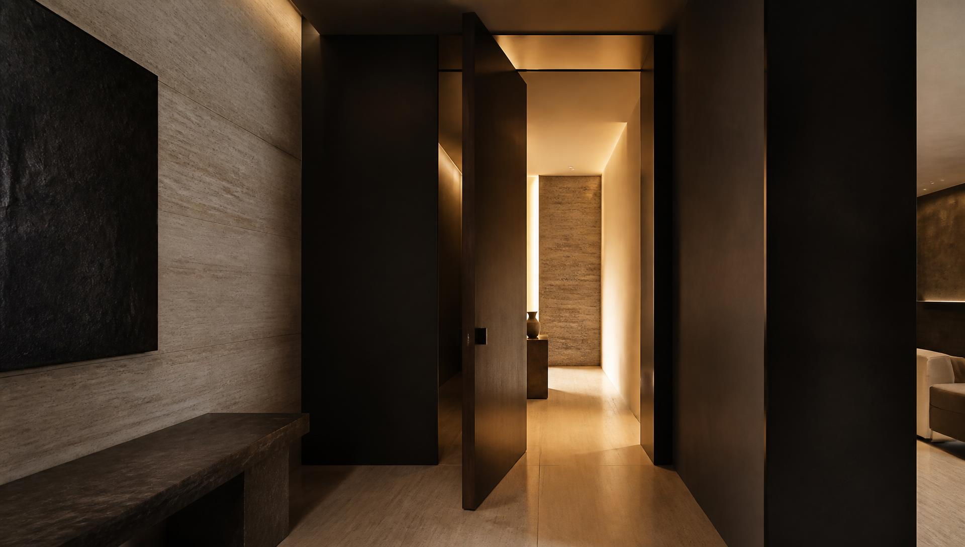 Luxury contemporary hallway with a tall dark doorway opening into warm light